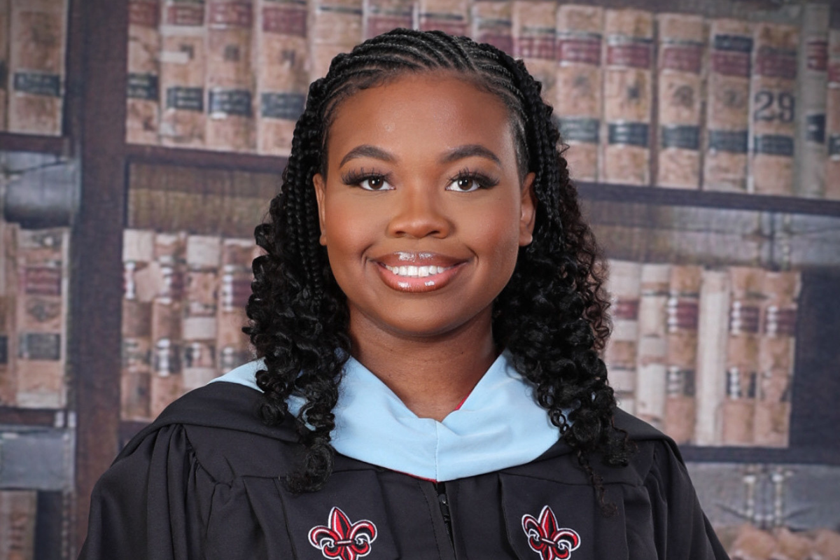 Masters in Gifted Education graduate smiles for portrait in black UL Lafayette master's regelia. 